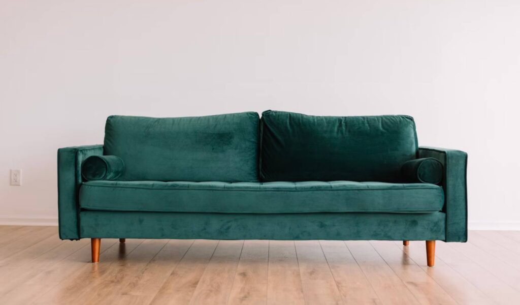 En grønn sofa med en hvit bakgrunn.